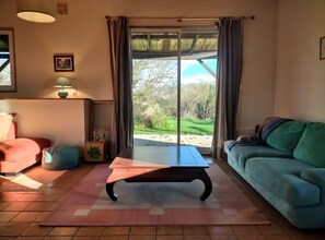 A living room with a sofa, a coffee table, a lamp, and a view through a sliding glass door.