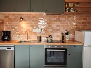 A kitchen with a dishwasher, oven, and a coffee maker.