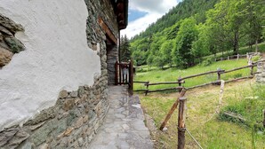 A stone pathway leading to a rustic wooden building with a wooden fence and lush greenery in the background. - Room 'Camera 5 - Doppia' with Mountain View and Wi-Fi (Mont-Rion)