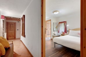 Una camera da letto con un letto, una panca di legno, un tavolino e uno specchio.