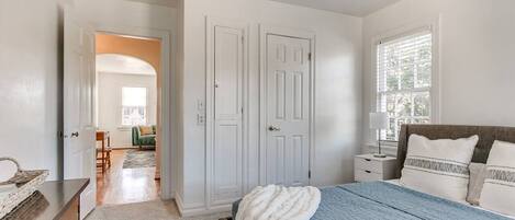A bedroom with a bed, a nightstand, a dresser, and a door leading to another room.
