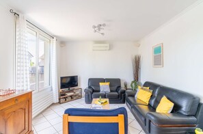 Ein Wohnzimmer mit Fernseher, zwei Sofas, einem Couchtisch und einem Holzschrank.