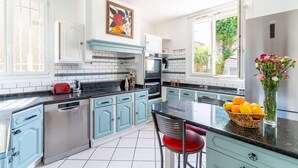 A modern kitchen with teal cabinetry, a black countertop, and a stainless steel dishwasher. - Entire Home · 1000m² Garden · Terrace · 30min from Paris (Conflans-Sainte-Honorine)