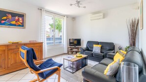 A living room with a sofa, a chair, a coffee table, a TV, and a painting on the wall. - Entire Home · 1000m² Garden · Terrace · 30min from Paris (Conflans-Sainte-Honorine)