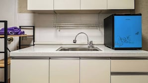 Una cocina con armarios blancos, un lavamanos de acero inoxidable y un refrigerador azul.