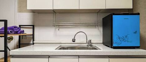 A kitchen with white cabinets, a stainless steel sink, and a blue refrigerator.