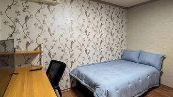 Une chambre à coucher comprenant un lit, un bureau, une chaise, un climatiseur et un papier peint à motifs.