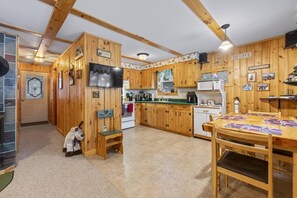 Ein Holzblockhaus-Interieur mit Küche, Essbereich und einem Hund.