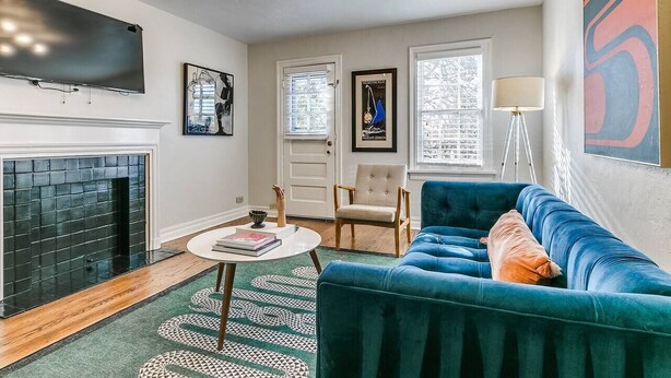 Ein Wohnzimmer mit Kamin, einem blauen Sofa, einem runden Couchtisch und einer modernen Pendelleuchte.