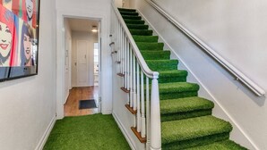 Eine Treppe mit grünen Teppichstufen und weißen Geländern.