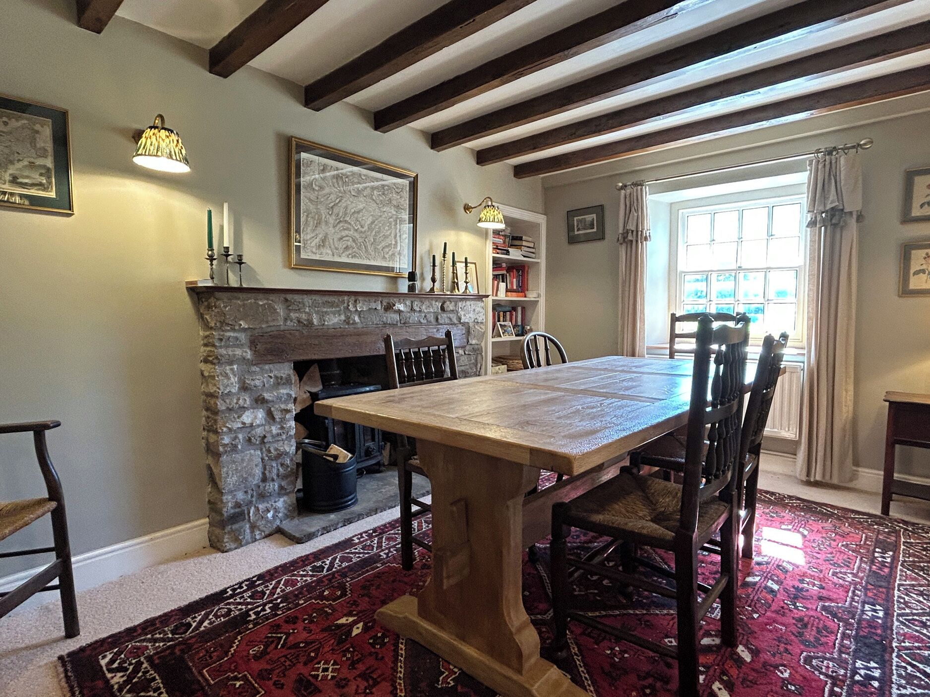 A dining area with a stone fireplace, a wooden table, and chairs.