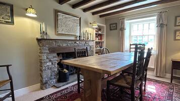 A dining area with a stone fireplace, a wooden table, and chairs.