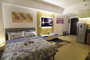 A modern hotel room with a bed, bedside table, TV, and a kitchenette. - NEW! Near Venice Grand Canal Mall, BGC & Airport, w/ SAUNA, POOL, GYM & NETFLIX (Taguig)