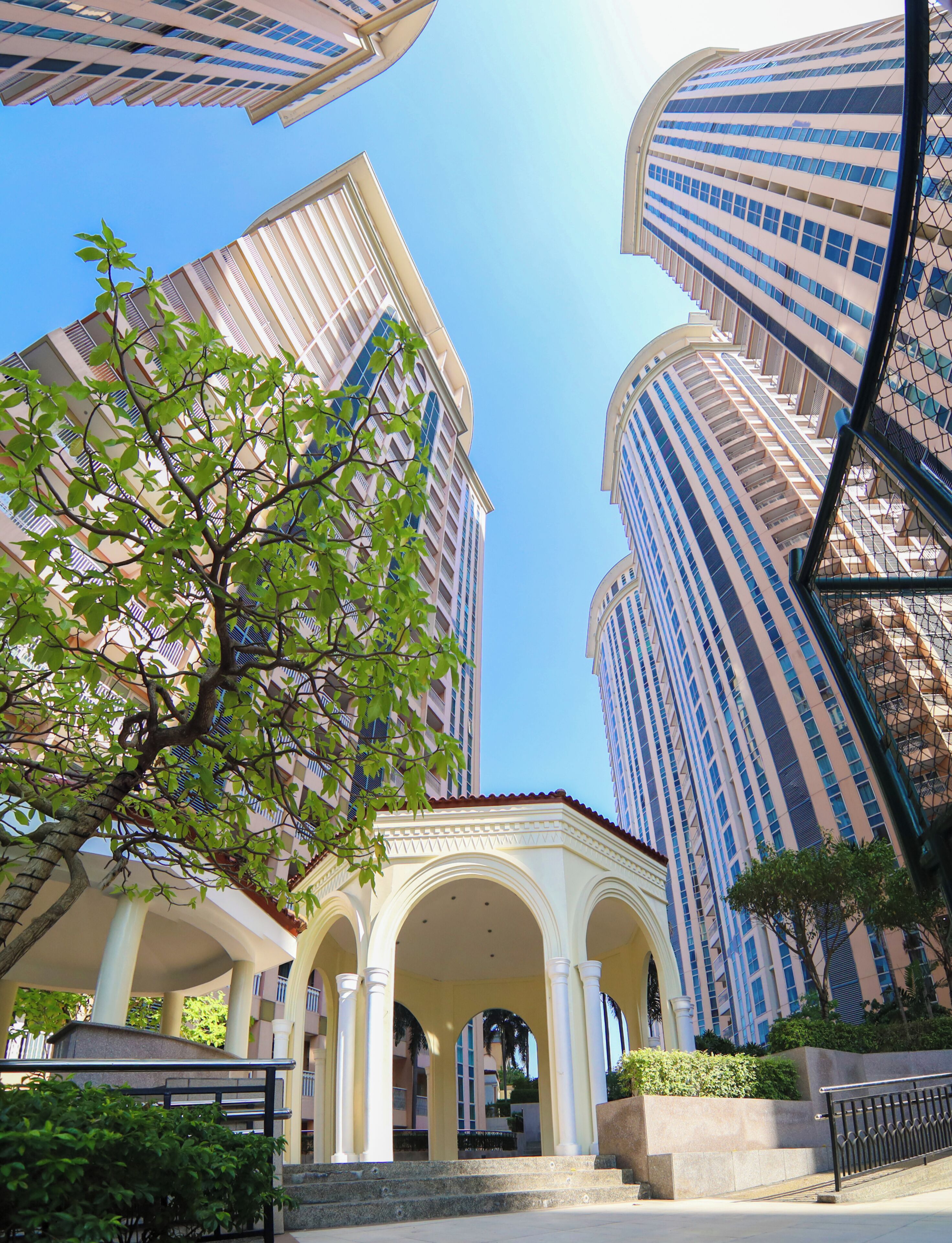 Un bâtiment moderne à étages, doté de grandes fenêtres et d’une cour intérieure avec des arcades.