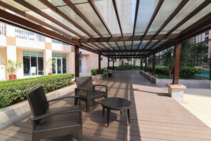 Ein überdachter Außenbereich mit Patio-Möbeln aus Rattan, einem kleinen runden Tisch und einer Sitzgruppe.