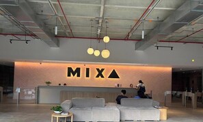 A reception area with a modern design, including a reception desk, seating area, and a visible ceiling with exposed beams and lighting fixtures. - Spectacular apartment in the town, surrounded by nature, parks and restaurants. (Medellín)