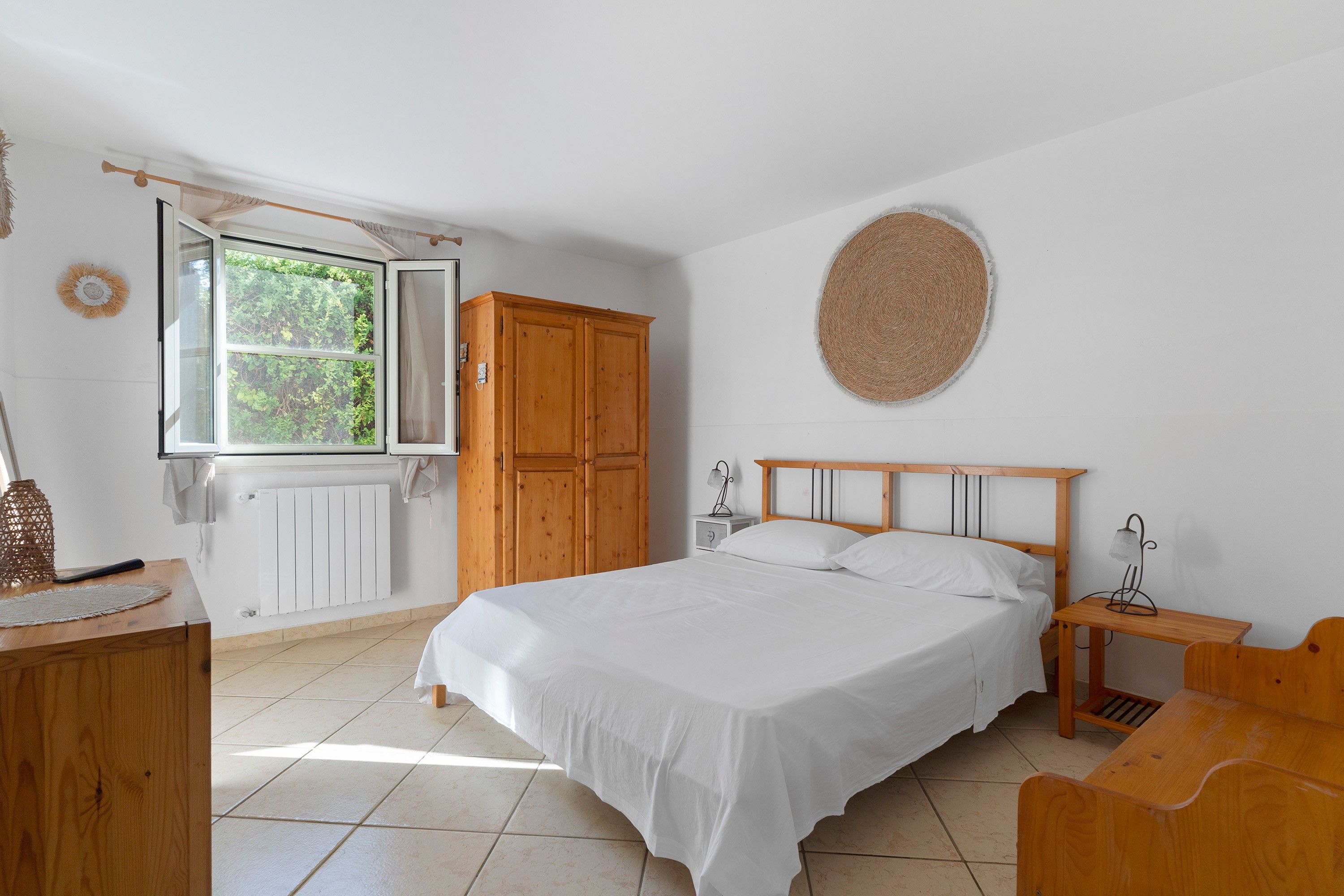 Une chambre à coucher comprenant un lit, une armoire en bois, une table de chevet et un élément de décoration circulaire fixé au mur.