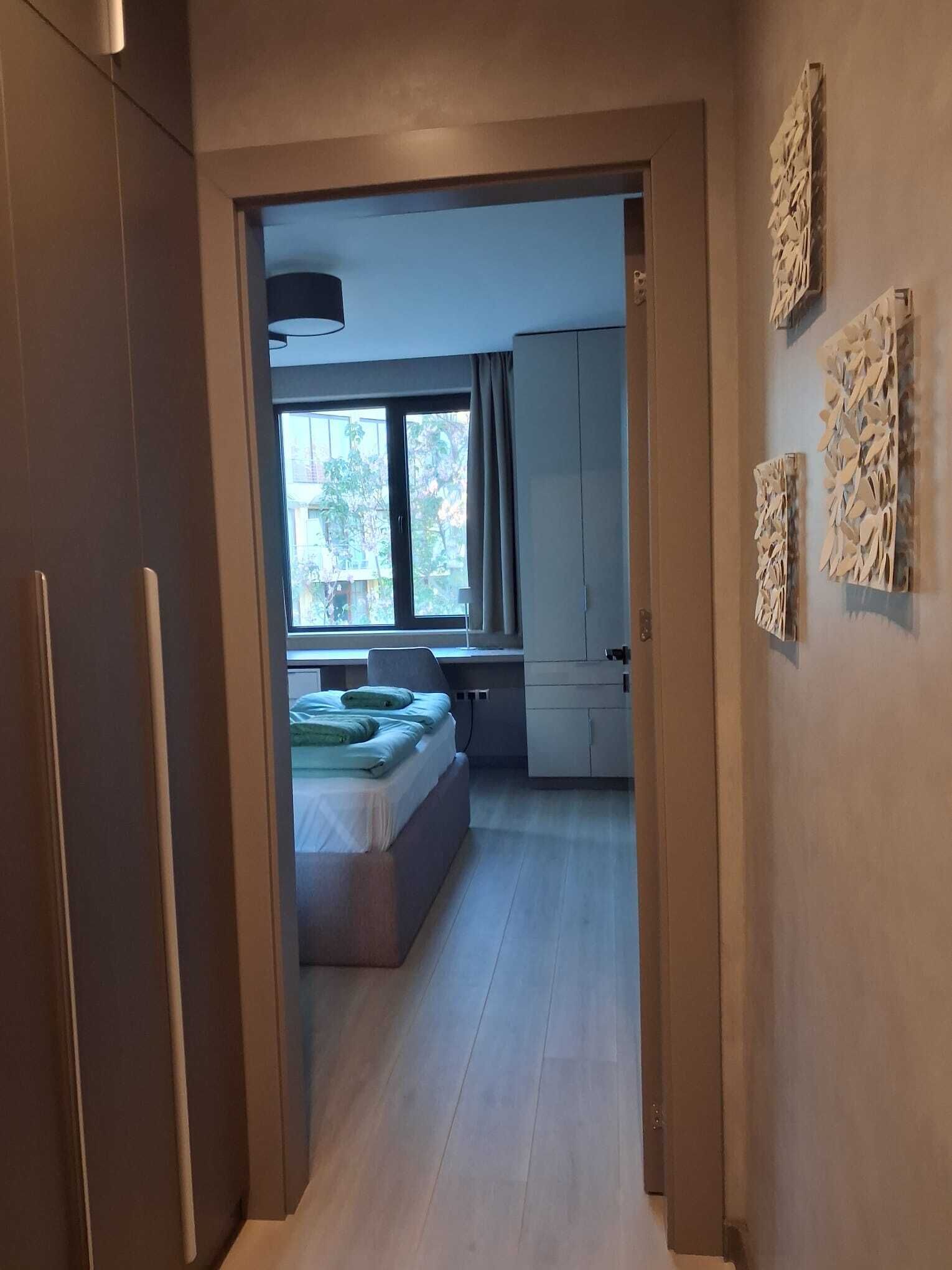 A modern interior with a bed, a desk, and a window with curtains.