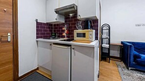 Una cocina compacta con microondas, lavamanos y un mueble pequeño.