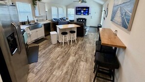 A compact kitchen with a refrigerator, sink, and bar stools.