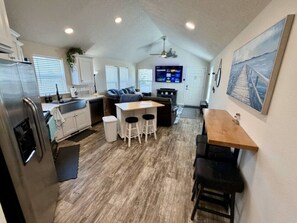 A compact kitchen with a refrigerator, sink, and bar stools. - The Bungalow – Escape, Explore, Enjoy (Garden City)