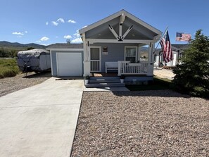 A single-story building with a porch, a garage, and an American flag. - The Bungalow – Escape, Explore, Enjoy (Garden City)
