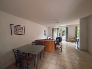 A spacious living area with a dining table, chairs, a kitchen counter, and a television. - Bright house with terrace and garden in Fréjus (Fréjus)