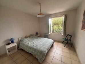 A bedroom with a bed, a nightstand, a chair, a window, and a ceiling fan. - Bright house with terrace and garden in Fréjus (Fréjus)