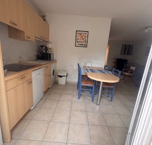 A compact kitchen with a dishwasher, microwave, and a small table with chairs. - Bright house with terrace and garden in Fréjus (Fréjus)