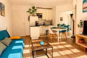 Ein gemütlicher, kleiner Wohnbereich mit Küchenzeile, Essbereich und einer Couch mit Kissen.