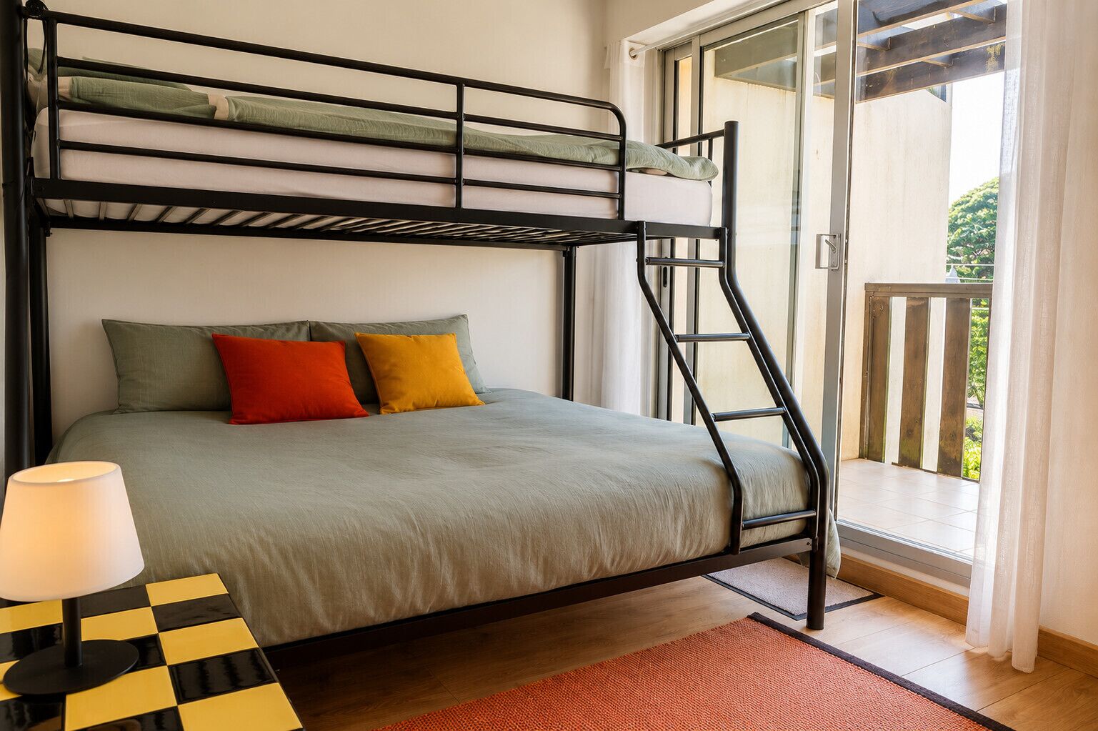 A bunk bed with a ladder, a checkered table, and a lamp.