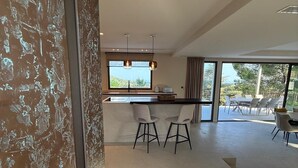 Uma cozinha moderna com uma janela grande, dois bancos de bar e um espaço de refeições com mesa e cadeiras.