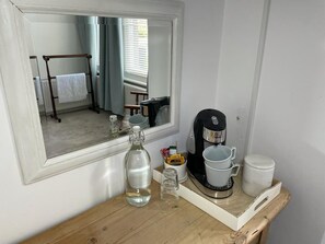 A bathroom with a wooden vanity, a coffee maker, a bottle, and a cup. - Poplars Farm (Henlow)