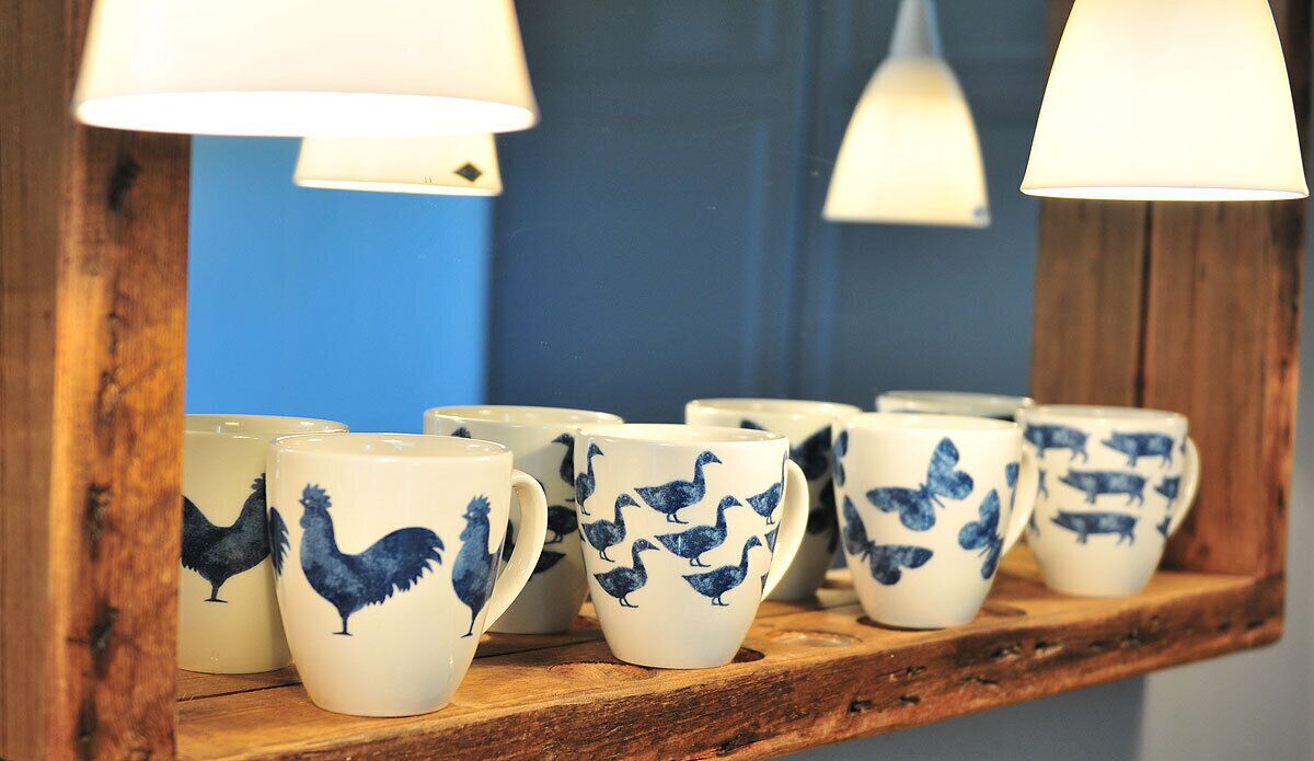 Una estantería de madera con tazas de cerámica decoradas con estampados de animales.