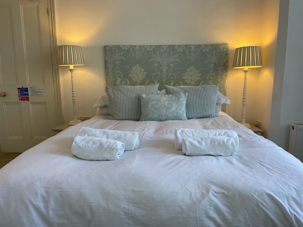 A neatly made bed with white linens and pillows, two bedside lamps, and a patterned headboard.