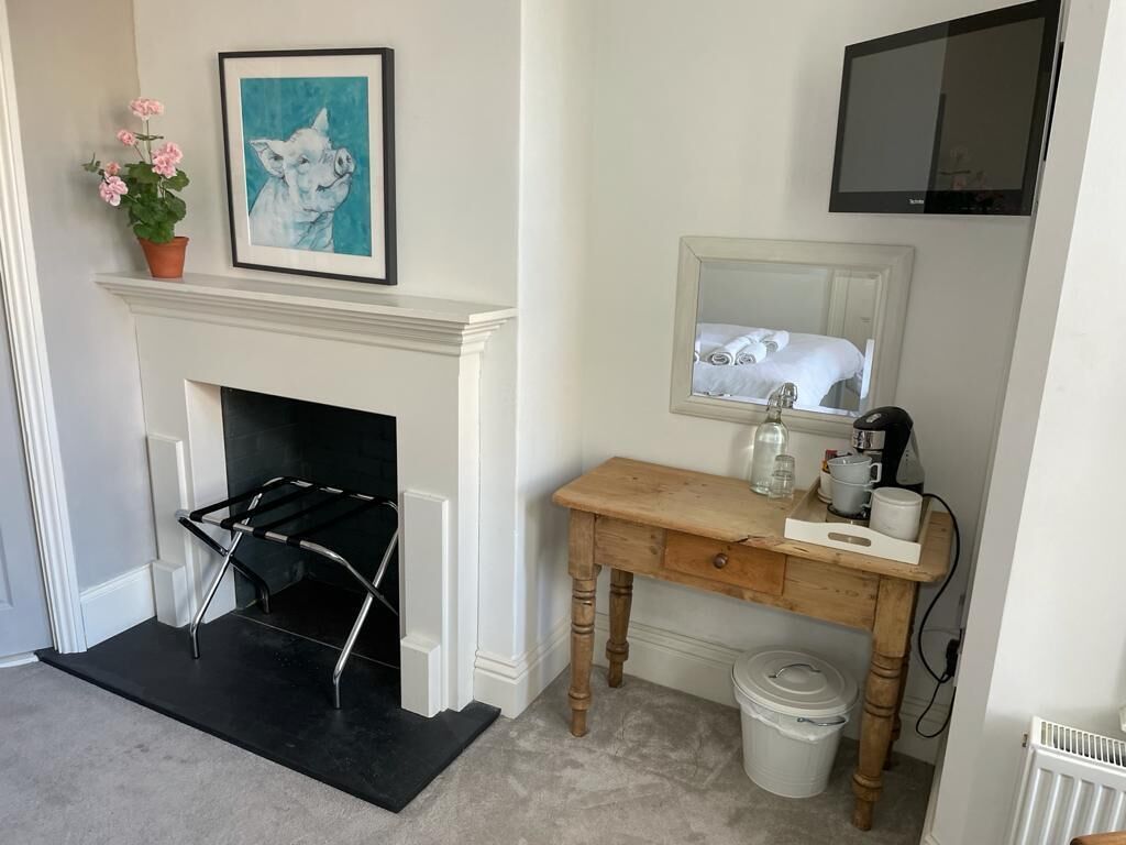 A room with a fireplace, a wooden desk, a mirror, and a television.
