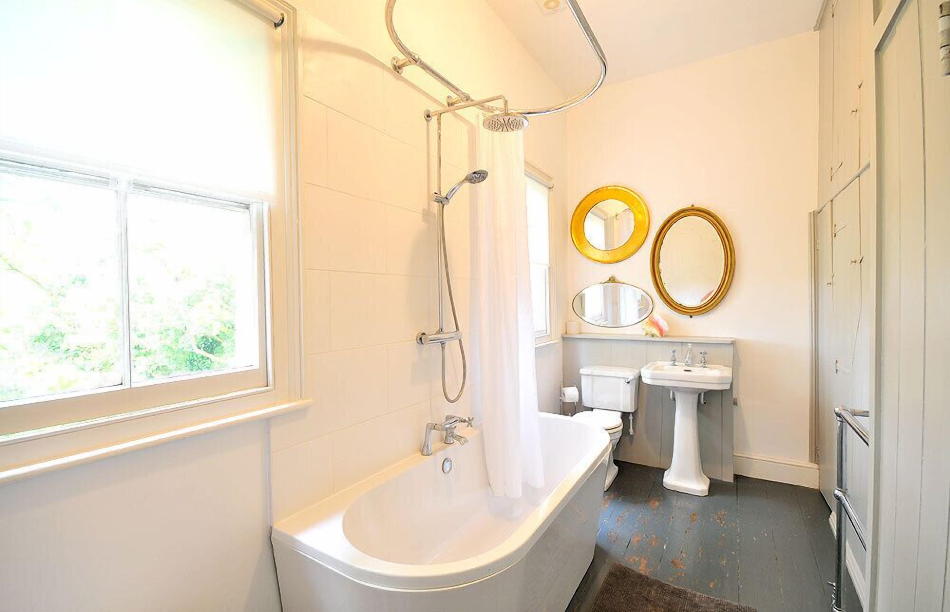 A bathroom with a bathtub, a shower, a sink, and two mirrors.