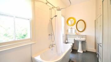 A bathroom with a bathtub, a shower, a sink, and two mirrors.