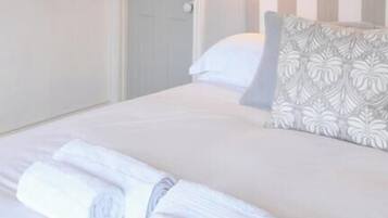 A neatly made bed with pillows, a bedside lamp, and rolled towels.