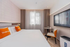 Una habitación de hotel con una cama grande, un televisor, una mesita y una silla.