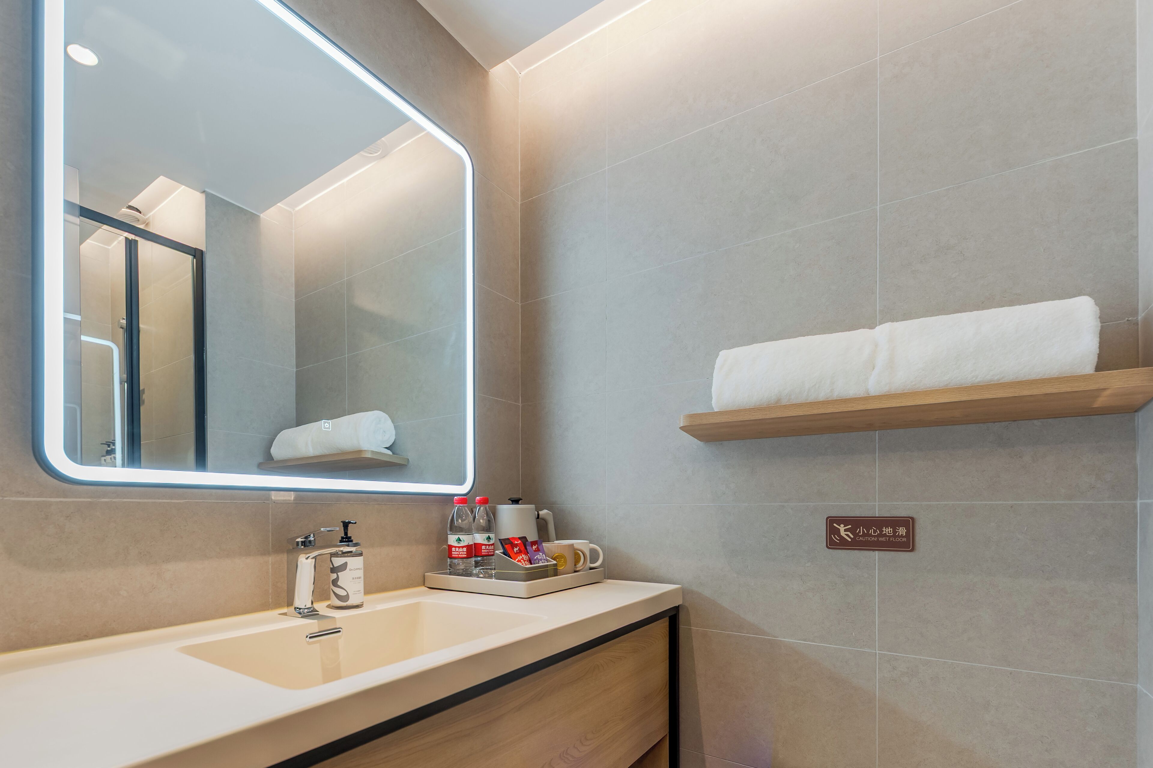 Une salle de bain moderne avec un grand miroir, un lavabo, un porte-serviettes et une étagère contenant des articles de toilette.