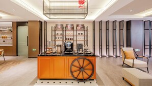 Una cafetería moderna con un mostrador central, estanterías con equipo para preparar café y una zona de estar con una silla y una mesa.