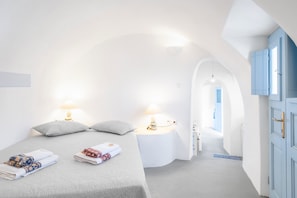 Et moderne hotelværelse med en seng, to sengeborde, et garderobeskab og en gang, der fører til et andet værelse.