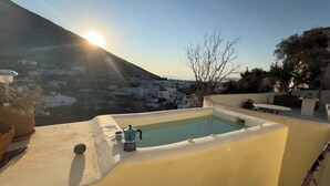 A rooftop terrace with a pool, a coffee maker, and a view of a town and mountain. - Thera Bliss "Hideaway" Private Jacuzzi by MΡS (santorini)