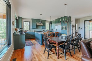 Une cuisine moderne avec des meubles de couleur turquoise, un îlot central et un coin repas doté de chaises en bois.