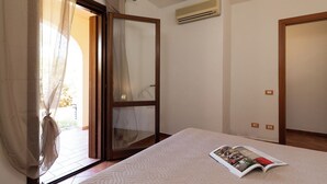 A bedroom with a bed, a magazine, a sliding glass door, and an air conditioning unit.