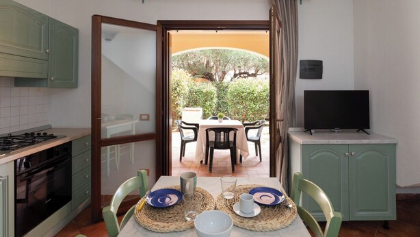 A kitchen with a dining area, a TV, and a view of the garden.