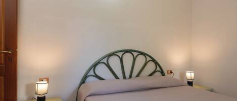 A single bed with a headboard, two bedside lamps, a nightstand with a drawer, and a book on the bed.