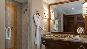 Ein Badezimmer mit begehbarer Dusche, einem Waschtisch mit großem Spiegel und einem Handtuchhalter.