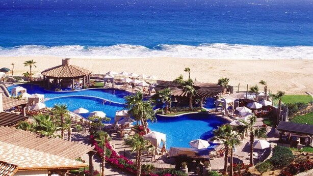 Ein Resort mit mehreren Schwimmpools, Zugang zum Strand und Palmen.